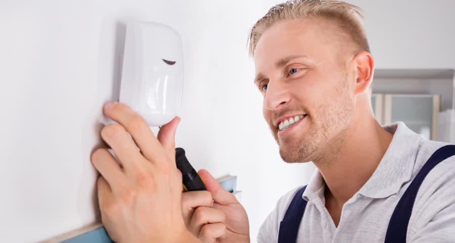 Man installing a motion detector inside a home